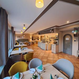 a restaurant with tables and chairs and a kitchen at Hotel-Ferienwohnungen Cafe Maarblick in Schalkenmehren