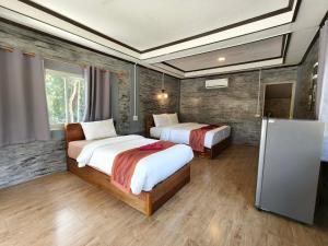 a hotel room with two beds and a refrigerator at Khao Sok Nung House in Khao Sok National Park