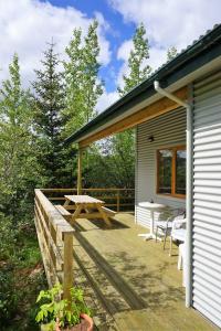 una terrazza con tavolo da picnic e panchine su una casa di Middalskot Cottages a Laugarvatn