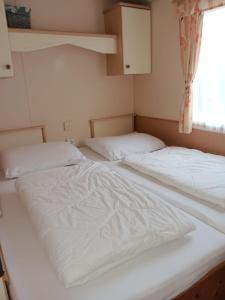 two white beds in a room with a window at 't Kotje Ouddorp in Ouddorp