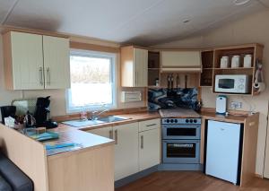 a small kitchen with white cabinets and a refrigerator at 't Kotje Ouddorp in Ouddorp
