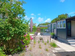 a garden with a house with a fence and flowers at 't Kotje Ouddorp in Ouddorp +5 photos