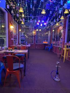 a dining room with tables and chairs and purple lights at Backpacker Storey in Bīr