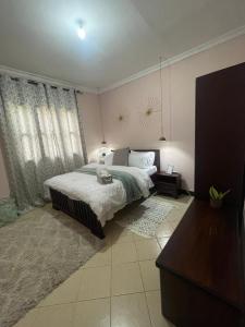 a bedroom with a bed and a large window at Serene homes in Mwanza