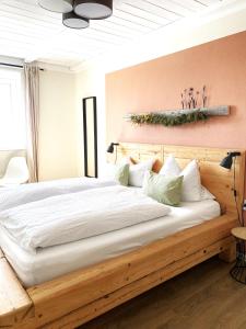 a bedroom with a wooden bed with white sheets and pillows at Wiesen-Hof in Günzach