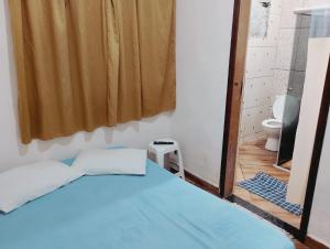 a bedroom with a blue bed and a toilet at quarto casal in Aparecida