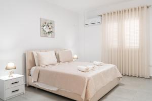 a white bedroom with a bed with two towels on it at Greca Apartments in Sauk