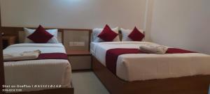 a bedroom with two beds with red and white sheets at Hotel Eden Palace in Trichūr