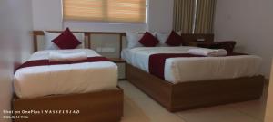 two beds sitting next to each other in a room at Hotel Eden Palace in Trichūr