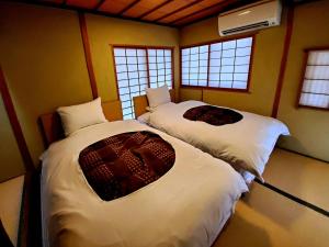 two beds in a room with two windows at Yufuin Santoukan in Yufu +86 photos