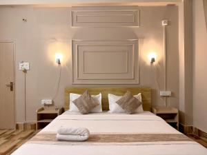 a bedroom with a large white bed with two lamps at Restel Guest House in Guwahati