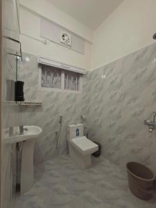 a bathroom with a white toilet and a sink at Restel Guest House in Guwahati +30 photos