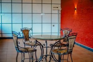 a table with four chairs and a glass top at Akruthi Palm Pavilion Resort in Aldūr