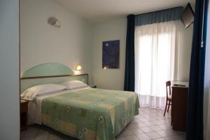 - une chambre avec un lit doté d'un couvre-lit vert et d'une fenêtre dans l'établissement Hotel Gli Ulivi, à Soverato Marina