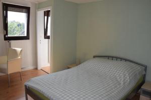 ein Schlafzimmer mit einem Bett, einem Fenster und einem Stuhl in der Unterkunft Maisonette im Hof Krupp in Bruchhausen