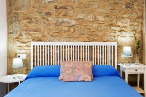 Un dormitorio con una cama azul con dos mesitas de noche. en Pensión Rua Nova, en Santiago de Compostela