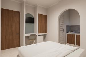 a white bedroom with a bed and a chair at Mecutan Guest House in Jimbaran