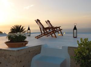 two wooden chairs sitting on a patio overlooking the ocean at OIA UNIQUE HOMES by K&K in Oia