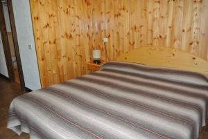 a bed in a room with a wooden wall at Residence Garden Appartamenti Solandra in Mezzana