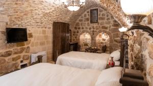 a bedroom with two beds in a room with stone walls at Vezir Konağı Hotel in Mardin