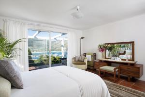 a bedroom with a bed and a desk and a window at Poseidon Guest House in Hout Bay