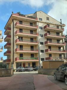 a tall apartment building with cars parked in a parking lot at Elisabeth home in Modica