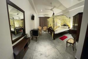a bedroom with a bed and a table and a mirror at Belgi Guest House in Balapitiya