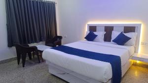 a bedroom with a large bed with blue pillows and a desk at HoTEL JAGAPATHI INTERNATIONAL in Vijayawāda