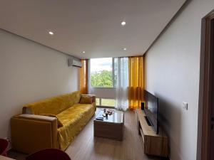 a living room with a yellow couch and a television at L'Aparté des hibiscus in Les Trois-Îlets