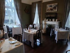 a dining room with tables with white table cloth at Greenland House B&B in Castletown