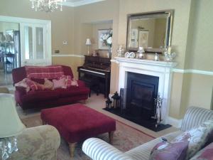 a living room with a fireplace and a piano at Drumhierney Lodge in Leitrim