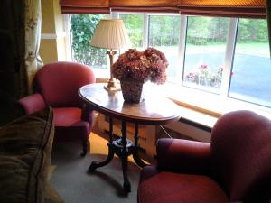 a table with a lamp and flowers on it in front of a window at Drumhierney Lodge in Leitrim