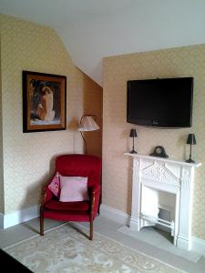 a living room with a red chair and a fireplace at Drumhierney Lodge in Leitrim