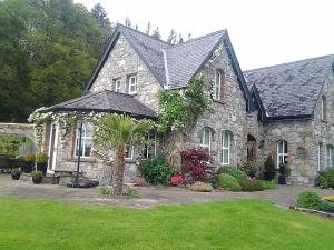 uma grande casa de pedra com uma árvore em frente em Drumhierney Lodge em Leitrim