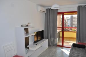 een woonkamer met een televisie en een balkon bij Apartment Eva Mar in Benidorm