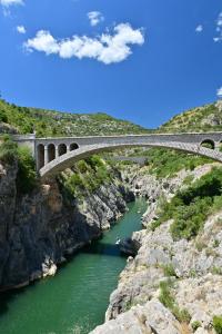 a bridge over a river next to a cliff at L'Oustal des Rameaux in Brissac