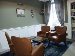 a living room with chairs and a table and a window at Greenland House B&B in Castletown