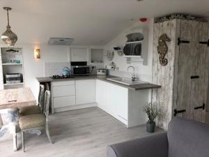 a kitchen with white cabinets and a sink and a table at West mouse view in Holyhead