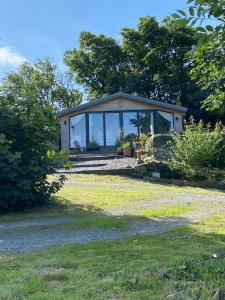 a small house with glass windows on a lawn at West mouse view in Holyhead