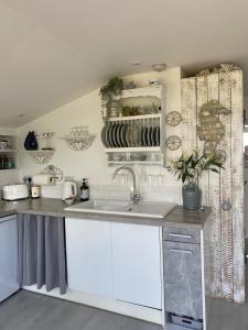 a kitchen with white cabinets and a sink at West mouse view in Holyhead +23 photos