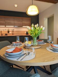 a wooden table with plates and glasses and a vase of flowers at Alte Remise Blankenburg in Blankenburg