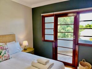 a bedroom with a bed and a window with a balcony at The Botanic Venus in Paarl