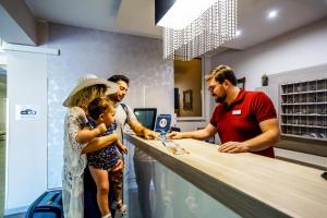 Eine Gruppe von Menschen steht mit einem Kind um einen Tresen herum. in der Unterkunft Hotel Orizzonte Blu in Tropea