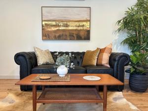 a living room with a black couch and a coffee table at Kowhai Apartment-Ground Floor in Pukekohe East