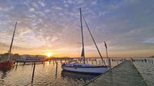 a sailboat is docked at a dock with the sunset at Ferienhaus unterm Reetdach in Ostseebad Sellin