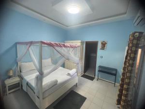 a bedroom with a white bed with a canopy at Appartement meublé avec Spa jacuzzi privatif in Mbour