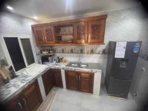a kitchen with wooden cabinets and a black refrigerator at Appartement meublé avec Spa jacuzzi privatif in Mbour