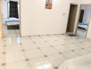 a room with a white wall and a tiled floor at Chetanya Homestay in Puttaparthi +2 photos