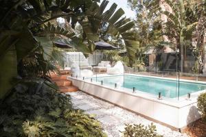 a swimming pool in a garden with aitatingfficient at Moso House Pearl Beach in Pearl Beach
