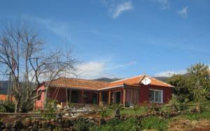 una casa rossa con una recinzione di fronte di Little Norway in Madeira ad Arco da Calheta